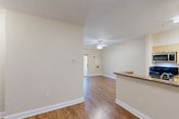 Located at 525 Washington St in Hanover, MA, this two-bedroom, two-bathroom residence offers a practical and comfortable single-floor layout. The open-concept living and dining area is anchored by rich hardwood-style flooring, neutral warm-toned walls, and a ceiling fan with light fixture. A sliding glass door fills the space with natural light and leads directly to a private patio, creating a seamless indoor-outdoor connection.

The kitchen is efficiently designed with cream cabinetry, granite-style countertops, stainless steel appliances including a range, microwave, and refrigerator, and tile flooring. A breakfast bar peninsula connects the kitchen to the main living area, enhancing the open flow.

Both bedrooms feature plush carpet flooring and neutral walls, with the primary bedroom offering generous proportions and ample space. Three closets are distributed throughout the residence, providing practical storage. The bathrooms are finished with tile flooring and white cabinetry; one bathroom features a tub/shower combination equipped with accessibility grab bars and a handheld showerhead. The overall ambiance is clean, bright, and move-in ready, with a cohesive neutral palette throughout.