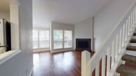 This two-story home offers a well-organized layout designed for comfortable everyday living. The main level centers around a spacious living area finished with rich hardwood flooring and anchored by a tile-surround wood-burning fireplace. Large front-facing windows flood the room with natural light and offer views of the surrounding greenery. A white-railed staircase connects the two floors, adding a clean architectural element to the open living space.

The kitchen is thoughtfully designed with white cabinetry extending to the ceiling for generous storage, light-toned countertops, stainless steel appliances including a range and over-the-range microwave, and tile flooring. A pass-through counter with an additional sink opens the kitchen toward the living and dining areas, enhancing the sense of openness and connectivity.

The bedrooms are carpeted for comfort and include ceiling fans for climate control. One bedroom features dual reach-in closets, while another includes a spacious walk-in closet outfitted with wire shelving on both sides, providing excellent storage capacity. The bathroom includes a full tub-shower combination with white tile surround, wood-look flooring, a single vanity with a light countertop, and a mirror. Textured ceilings are consistent throughout the home, contributing to its classic residential character.