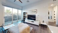 Located at 10650 Dean Martin Dr in Las Vegas, NV, this well-appointed 1-bedroom, 1-bathroom residence offers a thoughtfully designed open-concept layout with contemporary finishes throughout. Rich dark hardwood flooring flows seamlessly across the main living areas, anchoring the modern aesthetic.

The kitchen is a standout feature, showcasing dark walnut cabinetry, white subway tile backsplash, quartz countertops, and a full suite of stainless steel appliances including a French door refrigerator, dishwasher, and gas range with a wall-mounted hood. Open shelving adds both function and style, while a sleek kitchen island with seating provides an inviting dining space.

The living room is bright and airy, featuring a ceiling fan, recessed lighting, and large sliding glass doors that open to a private balcony overlooking lush outdoor greenery — flooding the space with natural light. The bedroom offers its own balcony access, plush carpeting, and a spacious closet.

The bathroom is finished with large-format white wall tiles, a soaking tub with an overhead shower, a dark-countered vanity with walnut cabinetry, and hardwood-style flooring. A hallway connects all rooms efficiently, completing this clean and functional floor plan.