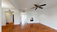 This single-story space showcases a thoughtful blend of Southwestern-inspired design and practical modern updates. The main living area is immediately distinctive, featuring warm terracotta tile flooring that extends throughout the common spaces, crisp white walls, and a standout arched fireplace with a raised brick hearth serving as a focal point. Recessed lighting and a ceiling fan complement the room, while a sliding glass door with vertical blinds fills the space with natural light and provides outdoor access.

The kitchen is equipped with dark espresso cabinetry, granite-style countertops, and stainless steel appliances including an electric range and over-the-range microwave. A window above the counter allows for additional natural light. The layout connects efficiently to the main living areas.

The bedrooms transition to rich wood-style laminate flooring, offering a warm contrast to the tiled common areas. Each room includes a ceiling fan and windows that bring in natural light with views of surrounding greenery. Sliding glass door access is available in at least one bedroom.

The bathroom features a tub-shower combination with white tile surround accented by a decorative mosaic tile border, dark cabinetry, granite-style countertops, and light tile flooring, delivering a clean and cohesive aesthetic throughout.