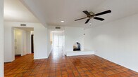 This single-story space showcases a thoughtful blend of Southwestern-inspired design and practical modern updates. The main living area is immediately distinctive, featuring warm terracotta tile flooring that extends throughout the common spaces, crisp white walls, and a standout arched fireplace with a raised brick hearth serving as a focal point. Recessed lighting and a ceiling fan complement the room, while a sliding glass door with vertical blinds fills the space with natural light and provides outdoor access.

The kitchen is equipped with dark espresso cabinetry, granite-style countertops, and stainless steel appliances including an electric range and over-the-range microwave. A window above the counter allows for additional natural light. The layout connects efficiently to the main living areas.

The bedrooms transition to rich wood-style laminate flooring, offering a warm contrast to the tiled common areas. Each room includes a ceiling fan and windows that bring in natural light with views of surrounding greenery. Sliding glass door access is available in at least one bedroom.

The bathroom features a tub-shower combination with white tile surround accented by a decorative mosaic tile border, dark cabinetry, granite-style countertops, and light tile flooring, delivering a clean and cohesive aesthetic throughout.