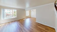 This two-story townhouse offers a well-organized layout across two levels, combining practical design with comfortable living spaces. The main level welcomes residents through a bright entryway featuring warm wood-look flooring that extends throughout the living and dining areas. The open living room is filled with natural light from multiple windows, complemented by crown molding and a pendant light fixture in the adjoining dining space. The galley-style kitchen is efficiently designed with white cabinetry, granite-look countertops, a stainless steel sink, and white appliances including a refrigerator, electric range, and built-in microwave. A clean staircase with white railings leads to the upper level, where two well-proportioned bedrooms are finished with plush neutral carpeting. Each bedroom benefits from windows that bring in generous natural light and offer views of the surrounding neighborhood and greenery. The full bathroom on the upper level features a clean, all-white tub and shower combination with tile surround and chrome fixtures. Throughout the townhouse, neutral wall tones and consistent finishes create a cohesive, move-in-ready environment suitable for a variety of living arrangements.