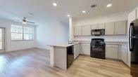 This single-story, 4-bedroom, 2-bathroom home offers a well-designed open-concept layout that maximizes functionality and flow. The combined kitchen and living area serves as the heart of the home, featuring light wood-look flooring, recessed lighting, and a ceiling fan. The kitchen is equipped with gray cabinetry, granite-look countertops, black appliances including a range and built-in microwave, and a peninsula with an integrated sink and dishwasher — ideal for both cooking and casual dining.

The living area is bright and airy, benefiting from natural light through large windows with blinds and access to an exterior door. Each of the four bedrooms is finished with plush carpeting and panel-style doors, offering a comfortable and quiet retreat. The bedrooms are supported by four closets throughout the unit, including a spacious walk-in closet outfitted with wire shelving systems for organized storage.

The two bathrooms are well-appointed, with one featuring a double-sink granite vanity, wood-look flooring, a soaking tub, and a large mirror — conveying a clean, modern aesthetic. Neutral white walls and consistent finishes throughout lend the home a cohesive, move-in-ready feel.