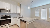 Located in Friendswood, TX, this single-story residence offers a thoughtfully designed layout with modern finishes throughout. The kitchen serves as a central highlight, featuring granite countertops, white shaker-style cabinetry, a tile backsplash, and a full suite of stainless steel appliances including a French door refrigerator, electric range, built-in microwave, and dishwasher. A peninsula with an integrated sink and pendant lighting above creates a natural connection between the kitchen and the adjacent living area. Crown molding adds a polished detail throughout the main living spaces. The living room is bright and open, lined with multiple windows and a glass-paneled exterior door that allows natural light to fill the space, complemented by a ceiling fan overhead. Bedrooms are carpeted and well-proportioned, offering a calm and comfortable atmosphere. The primary bedroom connects directly to a private bathroom, which includes a granite-top vanity, wood-look flooring, and a frameless glass-enclosed shower with full tile surround. A spacious walk-in closet with dual-level hanging rods provides generous storage. Additional bedrooms share access to the hallway and offer flexibility for various uses.