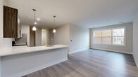Located at 450 W Westfield Ave in Roselle Park, NJ, this modern 2-bedroom, 2-bathroom residence offers a thoughtfully designed single-floor layout with a clean, contemporary aesthetic. The open-concept living and dining area flows seamlessly into a well-appointed kitchen, which features dark wood-grain cabinetry, quartz countertops, a subway tile backsplash, stainless steel appliances — including a range with microwave and dishwasher — and a peninsula with pendant lighting that anchors the space. Light hardwood-style flooring extends throughout the main living areas, enhancing the bright, airy feel. A large window in the living area invites natural light into the space. The two bedrooms are carpeted for comfort; the primary bedroom is generously sized and is served by its own bathroom, while the second bedroom also benefits from natural light. Both bathrooms are finished with large-format tile flooring, wood-grain vanity cabinetry, and clean white countertops. Additional conveniences include five closets, a dedicated laundry area, a utility room, and multiple hallways providing a well-organized flow throughout. The overall design is modern and neutral, offering a move-in-ready environment with quality finishes at every turn.