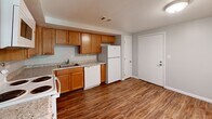 Located at 1717 Kuntz Rd in Erie, Pennsylvania, this single-floor unit offers a practical and well-organized layout accommodating three bedrooms and a kitchen within a compact footprint. The kitchen is a functional highlight, featuring warm honey-toned wood cabinetry, granite-look countertops, and durable wood-look vinyl flooring. White appliances including a range, microwave, dishwasher, and refrigerator are all included, providing a fully equipped cooking space. The living area benefits from natural light streaming through a large sliding glass door fitted with vertical blinds, offering views of the surrounding greenery and direct access to an outdoor deck structure. The three bedrooms are finished with neutral gray walls and plush wall-to-wall carpeting, contributing to a quiet and comfortable atmosphere. The spacious primary bedroom provides ample room and natural light through a window overlooking the outdoors. The additional bedrooms each feature closets with sliding doors and windows that bring in views of the tree-lined surroundings. Clean white trim and consistent neutral tones throughout create a cohesive, move-in-ready aesthetic. The overall layout is efficient and straightforward, making excellent use of the available space.