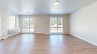 Located in Bend, Oregon, this two-story residence offers two bedrooms and five bathrooms across two well-proportioned floors. The main level features an open kitchen and living area with light wood-tone cabinetry, stainless steel appliances including a refrigerator, range, and microwave, and clean white countertops. Light hardwood-style flooring runs throughout the main living areas, contributing to a bright, contemporary feel. Large windows with blinds frame views of the surrounding ponderosa pines, and a door leads to an outdoor balcony, where a wood-decked exterior with metal railings overlooks the tree-lined surroundings under Oregon's open sky. The upper floor houses both bedrooms, each fitted with plush carpet and windows that bring in natural light and greenery views. The generously sized primary bedroom provides a comfortable retreat. The five bathrooms are finished with wood-toned vanities, white quartz countertops, large mirrors, and wood-look flooring, with some featuring accessibility grab bars. A staircase connects the two floors, and hallways on each level provide efficient circulation. Throughout, the neutral color palette, clean lines, and modern fixtures create a cohesive and functional living environment suited to the Pacific Northwest lifestyle.