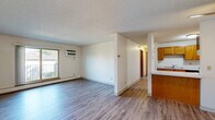 Located at 2488 Malmquist Ave in Red Wing, MN, this single-floor, two-bedroom, one-bathroom unit offers a practical and well-organized layout across a comfortable footprint. The open living area is finished with light-toned hardwood-style flooring, a textured ceiling, and a wall-mounted AC unit alongside baseboard heating. A sliding window overlooks an outdoor balcony, allowing natural light to fill the space. The living area flows seamlessly toward a peninsula that separates it from the galley-style kitchen, which features warm oak cabinetry on both sides, white appliances including a refrigerator, dishwasher, and electric range, and light countertops providing ample prep space. A hallway connects the main living area to the bedrooms and bathroom. The primary bedroom is a well-proportioned room with a built-in closet featuring bi-fold oak doors and carpet flooring. The second bedroom is similarly carpeted and includes a large window with views of the surrounding greenery. The full bathroom is clean and functional, offering a tub/shower combo, a wood-toned vanity with a white countertop, and matching hardwood-style flooring. Throughout the unit, neutral wall tones and consistent finishes create a cohesive and move-in-ready atmosphere.