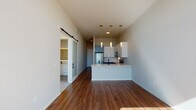 Located at 609 S Cascade Ave in Colorado Springs, Colorado, this contemporary single-floor residence showcases a thoughtfully designed open layout with high-end finishes throughout. The living area features warm hardwood flooring that flows seamlessly into the kitchen, creating a cohesive and inviting atmosphere. Large floor-to-ceiling windows and a sliding glass door open to a private balcony, flooding the space with natural light and offering elevated views of the surrounding Colorado landscape.

The kitchen is a standout feature, appointed with two-tone cabinetry — crisp white upper cabinets paired with slate-gray lower cabinets, both accented with brushed gold hardware. A quartz waterfall peninsula, matte black fixtures, stainless steel appliances including a refrigerator, electric range, built-in microwave, and dishwasher, and a decorative diamond-pattern tile backsplash complete the space. Statement pendant lighting with gold accents adds a refined touch overhead.

A sliding barn door with a frosted glass panel adds architectural interest while providing access to additional areas, including a walk-in closet with built-in cabinetry. The bathroom is clean and modern, featuring large-format marble-style wall tiles surrounding the soaking tub and shower combo, complemented by matte black fixtures and neutral tile flooring. The overall design balances modern urban aesthetics with functional, comfortable living.