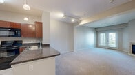 Located at 329 E Fifth St in Loveland, Colorado, this two-bedroom, one-bathroom residence offers a practical and comfortable layout across a single floor. The open-concept kitchen is a standout feature, equipped with warm wood cabinetry, dark granite-style countertops, black appliances including a range and refrigerator, tile flooring, and a peninsula with a sink that looks out into the living area. Pendant lighting and a built-in shelving unit add functional character to the space. The living room is carpeted and features a cozy tiled fireplace, creating a welcoming focal point, with a window providing natural light. The primary bedroom is a well-proportioned retreat with soft carpet, a window with blinds, and a closet with built-in shelving and hanging rods. The second bedroom offers similar neutral tones and carpeted flooring with tray ceiling detailing. The full bathroom is finished with light tile flooring, a tub-shower combination with white tile surround, a vanity with wood cabinetry, and a large mirror. Track lighting and recessed fixtures illuminate the common areas efficiently. The overall palette is neutral and clean, giving the space a move-in-ready, adaptable feel.