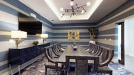 This single-floor space is a well-appointed meeting or private dining room designed with a bold, contemporary aesthetic. The walls are finished in striking horizontal blue and white stripes, creating a dynamic visual rhythm that defines the room's character. A tray ceiling with integrated ambient lighting adds architectural depth and a refined sense of elevation to the space.

At the center of the room sits a substantial rectangular table crafted from dark, textured wood, surrounded by a set of curved, upholstered chairs in a charcoal finish that blend style with comfort. Overhead, a sculptural sputnik-style chandelier with globe bulbs serves as a dramatic focal point, complementing the room's modern sensibility.

Along one wall, a dark navy sideboard provides functional storage while reinforcing the room's cohesive color palette. A large flat-screen television is mounted nearby, making the space well-suited for presentations or media-driven gatherings. Decorative gold artwork panels and tall dried botanicals in a white vase add artistic touches, while a patterned area rug grounds the seating arrangement. The overall ambiance is sophisticated, bold, and versatile.