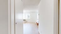 Located at 720 W 27th St in Los Angeles, CA, this single-floor, one-bedroom, one-bathroom unit offers a compact yet functional layout designed to maximize every square foot. The spacious main living and sleeping area is finished with light-toned hardwood flooring throughout, lending a clean and airy feel to the interior. White walls and a textured ceiling complement the bright aesthetic, while a ceiling fan provides year-round climate comfort. Two large windows dressed with vertical blinds allow natural light to fill the room, and a wall-mounted air conditioning unit provides additional climate control. The bedroom area comfortably accommodates a full-size bed and a workstation, demonstrating the room's generous proportions. A dedicated closet off the main room features built-in shelving and hanging space, offering organized storage — the water heater is also housed within this closet area. The bathroom is clean and functional, featuring a wide white vanity with an integrated sink, a large mirror, and a shower-tub combination enclosed with sliding glass doors. The overall ambiance of the unit is bright, minimalist, and move-in ready, making it a practical option in the University Park neighborhood of Los Angeles.