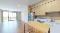 This well-appointed one-bedroom, one-bathroom residence at 850 Pacific Street in Stamford, Connecticut, offers a thoughtfully designed open-concept layout with modern finishes throughout. Warm hardwood-style flooring flows seamlessly across the entire space, lending a cohesive and inviting feel.

The kitchen is a standout feature, outfitted with light wood cabinetry extending to the ceiling for ample storage, sleek marble-style countertops, a full suite of stainless steel appliances including a gas range, microwave, dishwasher, and a French door refrigerator, plus a central island that doubles as a dining and prep surface.

The living area is bright and airy, benefiting from large sliding glass doors that open directly onto a private balcony. The balcony offers expansive views of the Stamford skyline and surrounding landscape, filling the interior with abundant natural light.

The spacious primary bedroom features herringbone-pattern hardwood flooring and its own set of sliding glass doors accessing the balcony, further enhancing the connection to outdoor views. Two closets, including a walk-in with built-in wire shelving, provide generous storage.

The bathroom is cleanly finished with a full tub-shower combination, white tile surround, and a vanity with ample counter space. Louvered closet doors and neutral wall tones complete the modern, functional aesthetic throughout.