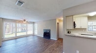Located at 1709 Cobb Crossing SE in Smyrna, Georgia, this single-floor home offers a well-designed layout with comfortable living spaces throughout. The open living area serves as the heart of the home, showcasing rich hardwood-style flooring, a textured ceiling, and a ceiling fan. A tile-surround fireplace anchors the main living space, adding both warmth and character. Large windows along the exterior walls flood the room with natural light and provide pleasant views of the surrounding greenery.

The kitchen is thoughtfully appointed with white cabinetry, granite-style countertops, a mosaic tile backsplash, and black appliances including a gas range, dishwasher, microwave, and refrigerator. Light wood-style flooring and a window above the sink complete the functional and attractive space.

The bedrooms feature plush carpeting, ceiling fans with light fixtures, and windows that bring in natural light. The primary bedroom is notably well-equipped with two closets, including a walk-in with built-in shelving, offering generous storage. The bathroom includes a full tub-shower combination with white tile surround and chrome fixtures.

A secondary living or flex room with large sliding-panel windows and hardwood-style flooring adds versatile space to this well-rounded home.