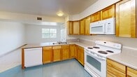 Located at 1450 N Main in Hartford, CT, this two-bedroom, one-bathroom unit offers a practical and well-organized single-floor layout. The kitchen is a functional highlight, featuring warm honey-toned wood cabinetry, ample counter space, and white appliances including a refrigerator, electric range, microwave, and dishwasher. Blue speckled tile flooring runs throughout the kitchen area, which also provides convenient access to a large closet near the entry door. The two bedrooms are bright and neutrally finished, with light-toned speckled tile floors and crisp white walls. The primary bedroom offers a comfortable footprint, while the second bedroom includes a double-door closet and a window with natural light and exterior views. Both rooms benefit from a clean, open feel. A connecting hallway links the rooms efficiently. The bathroom continues the consistent, clean aesthetic with tiled flooring, a grab bar, and a vanity with storage below. Throughout the unit, white six-panel doors, light-colored baseboards, and neutral walls create a cohesive, understated interior. The overall ambiance is clean, bright, and move-in ready, well-suited for practical, comfortable everyday living.