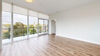 This single-floor unit offers four bedrooms, two bathrooms, and a thoughtfully arranged layout connected by multiple hallways and a dedicated closet. The open-concept kitchen and living area serves as the centerpiece of the space, featuring floor-to-ceiling windows and sliding glass doors that provide direct balcony access and sweeping views of the surrounding cityscape. The kitchen is outfitted with white flat-panel cabinetry, granite countertops, a large island, and stainless steel appliances, including a built-in microwave, dishwasher, and range. Light hardwood flooring runs consistently throughout the main living areas and bedrooms, contributing to a bright, cohesive aesthetic. The bedrooms are finished with neutral white walls and large windows that allow ample natural light. Two full bathrooms serve the unit; one features marble-style porcelain tile flooring, a white vanity with granite countertop, and a soaking tub, while the second includes a glass-enclosed walk-in shower with white subway tile. Throughout, the unit maintains a clean, contemporary design defined by an abundance of natural light and urban views.