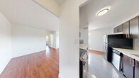 Located at 7 Elizabeth St N, Unit 202 in Mississauga, Ontario, this two-bedroom unit offers a well-organized layout across a single floor. Warm-toned hardwood flooring runs throughout the living areas and bedrooms, lending a cohesive and inviting feel to the space.

The combined kitchen and living room area provides an open, functional layout. The kitchen is equipped with rich dark-wood cabinetry extending to the ceiling for ample storage, stainless steel appliances including a full-size refrigerator and dishwasher, a double sink, and light tile flooring. The adjacent living room is bright and airy, featuring a wide picture window fitted with a baseboard heater that frames views of the surrounding Mississauga streetscape.

The primary bedroom is a well-proportioned room with large windows that allow generous natural light and offer views of the neighbourhood, including mature trees and nearby buildings. A second bedroom mirrors this bright character, also benefiting from a large window with outdoor views and hardwood floors.

A notable feature of one bedroom is the mirrored sliding closet doors, which amplify the sense of space. A hallway connects the bedrooms to a bathroom finished with warm tile. Clean white walls throughout the unit create a neutral, move-in-ready backdrop. The unit's position on the second floor contributes to pleasant elevated views of the surrounding area.