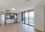 Located at 1500 NE Miami Place in Miami's vibrant Arts & Entertainment District, this high-rise residence offers a contemporary open layout with exceptional panoramic views of the Miami skyline and surrounding cityscape. Light wood-tone flooring flows throughout the living areas and bedrooms, complementing the clean, modern aesthetic of the space.

The open-concept living and dining area is anchored by expansive floor-to-ceiling sliding glass doors that lead to a private balcony, flooding the interior with natural light and framing sweeping city views. The kitchen is well-appointed with dark granite countertops, two-tone wood cabinetry, white marble-style tile flooring, and a full suite of stainless steel appliances including a refrigerator, range, and built-in microwave.

The bedrooms each feature large floor-to-ceiling or oversized windows showcasing impressive elevated views of Miami, with light-filled interiors and light wood flooring. The bathrooms are finished with elegant marble-style wall surrounds in the tub-shower combinations, with one bathroom featuring a warm wood vanity with granite countertop and a large mirror. Throughout the unit, the design emphasizes natural light, clean lines, and high-rise views that define upscale urban Miami living.