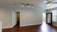 This single-floor residence at 5104 Retreat Hill Way in Asheville, NC offers a well-designed layout with consistent finishes throughout. The main living area is highlighted by rich, dark hardwood-style flooring, crown molding, and a ceiling fan, creating a polished and comfortable atmosphere. Track lighting adds a modern accent, while a glass-paned door opens directly to an outdoor balcony, allowing natural light to fill the space through multiple windows fitted with horizontal blinds.

The open layout connects the living area to the kitchen, which features dark espresso cabinetry, granite-style countertops, a double stainless steel sink, and black appliances including a range and built-in microwave. A pass-through counter visually links the kitchen to the main living space, enhancing the open feel.

Additional rooms include a generously sized secondary space with a ceiling fan, a natural-light window, and continued hardwood-style flooring—suitable as a bedroom or flexible living area. The bathroom is appointed with dark wood cabinetry, a granite-topped vanity, a large mirror, and coordinating flooring. The unit's neutral gray walls and cohesive design elements provide a clean, move-in-ready aesthetic throughout.