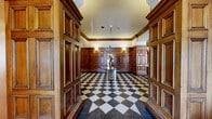 Located at 1400 N Lake Shore Drive in Chicago's prestigious Gold Coast neighborhood, this landmark lobby is a masterclass in classical architectural elegance. The space is defined by rich, floor-to-ceiling raised-panel wood walling that lines every corridor and seating area, conveying warmth and timeless sophistication throughout.

The striking black-and-white marble checkerboard flooring extends seamlessly across the entire lobby, anchoring the grandeur of the space. Overhead, ornately painted coffered ceilings adorned with gilded detailing and figurative murals serve as a breathtaking focal point, reflecting the building's historic character. Arched doorways with decorative ironwork add to the architectural drama, while wall-mounted sconces provide warm, ambient lighting throughout.

Multiple seating areas are thoughtfully arranged within the lobby, furnished with tufted leather sofas, upholstered armchairs, and contemporary accent tables — balancing classic design with modern comfort. A staffed reception desk is centrally positioned, offering a welcoming point of service. The lobby also features access to Salon Duo, a full-service salon with its own distinguished wood-framed entryway. Natural light filters in through arched entry doors, offering views of the surrounding tree-lined streetscape.