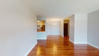 Located at 7410 Roosevelt Rd in Forest Park, IL, this single-floor unit offers a thoughtfully designed layout with warm, rich hardwood flooring throughout. The open living and dining area creates a welcoming, flowing space anchored by a classic chandelier and complemented by clean white walls and crisp white baseboards. A pass-through connects this area to the kitchen, which is equipped with stainless steel appliances including a range, over-the-range microwave, and dishwasher, alongside white cabinetry and a butcher block countertop. The bedrooms are generously proportioned, each featuring hardwood floors, natural light from well-positioned windows, and closet space — one bedroom includes a sliding glass door that invites additional light and outdoor access. The unit includes two bathrooms: one showcasing a granite-topped vanity with a framed mirror and open shelving, and another featuring a vessel sink atop a rich wood vanity with modern fixtures. The neutral, soft-gray color palette used throughout lends the space a clean, contemporary feel, while the consistent hardwood flooring ties each room together cohesively. The overall layout, as seen in the dollhouse view, is practical and well-proportioned, making efficient use of the available space.