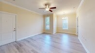 Located at 16215 Castle Top Ct in Fountain Inn, South Carolina, this single-floor residence offers a thoughtfully designed layout with a warm, neutral color palette throughout. Light wood-look flooring flows seamlessly across the main living and bedroom areas, complemented by tile flooring in the kitchen and bathroom, creating a cohesive and clean aesthetic.

The open living and dining area is highlighted by crown molding, a ceiling fan with integrated lighting, and an elegant chandelier, lending a polished feel to the shared space. Multiple windows allow natural light to fill the room, enhancing its bright and airy ambiance.

The kitchen is well-appointed with rich warm-toned cabinetry, granite-look countertops, and a full suite of stainless steel appliances including a refrigerator, range, microwave, and dishwasher. A hallway connects the kitchen directly to the bathroom, contributing to an efficient floor plan.

The bathroom features a tub-shower combination with a curved curtain rod, a warm wood vanity with a stone-top countertop, and tile flooring. A generously sized walk-in closet with multi-tiered wire shelving and hanging rods provides ample storage. The bedroom includes a pendant light fixture and direct access to the walk-in closet, rounding out this well-organized and comfortable home.