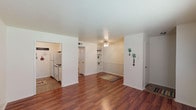 This single-story, 1-bedroom, 1-bathroom residence offers a thoughtfully designed layout that maximizes functionality and comfort. The main living area is anchored by rich, warm hardwood-style flooring that extends throughout, complemented by clean white walls and a ceiling fan that enhances the bright, airy atmosphere. A distinctive wainscoting detail and built-in shelving unit add architectural character to the living space, while natural light filters in through windows fitted with blinds.

The galley-style kitchen is efficiently arranged with white cabinetry lining both sides, granite-look countertops, a double basin sink, and white appliances including a refrigerator and range. Tile-style flooring grounds the kitchen and provides a practical, easy-care surface.

The bedroom is a comfortable retreat featuring plush carpeting, a ceiling fan with light fixture, and a window that invites natural light. It includes direct access to a spacious walk-in closet with built-in shelving, as well as a conveniently connected full bathroom. The bathroom features granite-look countertops, an undermount sink, a vanity mirror, and a shower-tub combination, all finished with tile-style flooring. The overall design of this home balances practicality with classic, welcoming details throughout.