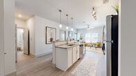 This single-story, one-bedroom, one-bathroom unit offers a thoughtfully planned layout that maximizes its compact footprint. The open-concept kitchen and living area serves as the heart of the space, where a galley-style kitchen with white shaker cabinetry, granite countertops, and stainless steel appliances—including a range, microwave, refrigerator, and dishwasher—flows seamlessly into a peninsula island with bar seating and pendant lighting overhead. Track lighting above the kitchen adds a modern touch, while wood-style luxury vinyl flooring runs throughout the main areas, providing a clean, cohesive aesthetic.

The living room benefits from multiple windows that invite natural light and includes a ceiling fan for comfort. A patio door provides an additional source of light and outdoor access. The bedroom is a well-proportioned retreat featuring two windows, a ceiling fan, and direct access to a dedicated walk-in closet outfitted with dual hanging rods and built-in shelving for organized storage.

The full bathroom is finished with granite countertops, white cabinetry, a large vanity mirror, and a shower-tub combination, maintaining the consistent, clean design language found throughout the space. Overall, the unit presents a bright, modern aesthetic with practical finishes and a functional single-floor layout.