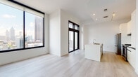 Located in the heart of Midtown Atlanta, this contemporary unit on Peachtree Street offers a refined, single-floor layout defined by clean lines, an all-white palette, and light-toned hardwood flooring throughout. Large, black-framed floor-to-ceiling windows flood the living area with natural light while framing striking views of the Atlanta skyline and surrounding urban landmarks, including notable historic architecture. A glass sliding door opens to a private balcony, extending the connection to the cityscape beyond.

The open-concept kitchen serves as a focal point of the living space, anchored by a sleek white waterfall island with an integrated sink. Premium stainless steel appliances, including a gas range with hood and a column refrigerator, are complemented by tall, handle-free white cabinetry and white tile backsplash. Recessed and track lighting illuminate the space efficiently.

The bedroom features generous proportions with its own large black-framed windows offering panoramic city views, continuing the unit's modern aesthetic. The bathroom is finished with large-format tile flooring, a dual-sink floating vanity with a frameless mirror, and a glass-enclosed walk-in shower, all contributing to a clean, spa-like atmosphere throughout.