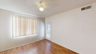 This single-floor residence offers a cohesive and functional layout finished with warm hardwood-style flooring that flows consistently throughout every room, lending the space a unified and inviting character.

The living area is generously proportioned, bathed in natural light courtesy of large windows fitted with vertical blinds. A ceiling fan provides year-round comfort, and a glass-panel door opens directly to an outdoor area, enhancing the sense of connection to the exterior.

The kitchen is thoughtfully designed with light maple cabinetry, dark countertops, and a full suite of white appliances including a range, over-the-range microwave, and refrigerator. A peninsula with a breakfast bar divides the kitchen from the living space, creating an open, interactive flow ideal for both cooking and entertaining. Track lighting overhead ensures the kitchen is well-lit throughout the day.

The bathroom features a single-sink vanity with light maple cabinetry and dark countertop surfaces, complemented by a large mirror and a bright Hollywood-style light bar above. The hardwood-style flooring continues here, maintaining design consistency across the unit.

Overall, the space presents a clean, neutral palette with practical finishes, making it a comfortable and move-in ready residence.