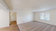 Located at 2900 Middle Rd in Bettendorf, Iowa, this two-bedroom, two-bathroom single-floor unit offers a practical and comfortable layout. The living room features a combination of warm hardwood-style flooring and plush carpet, with a textured ceiling and a front entry door that opens directly into the space. Natural light filters in through windows with views of surrounding greenery.

The galley-style kitchen is well-appointed with rich, warm-toned wood cabinetry, granite-look countertops, stainless steel appliances including a range and dishwasher, and easy-care hardwood-style flooring—offering efficient use of space for everyday cooking.

The spacious primary bedroom includes a large double-door closet and direct access to an en-suite bathroom, which features dark cabinetry with a white countertop vanity, hardwood-style flooring, and a tub-shower combination with tile surround. A second full bathroom mirrors this clean, contemporary aesthetic.

Both bedrooms are carpeted and receive natural light through sizable windows overlooking tree-lined outdoor views. A connecting hallway with additional closet space provides practical storage. Throughout, the neutral color palette and clean finishes create a bright, move-in-ready atmosphere.