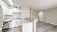 Located at 10 E Bell Rd in Phoenix, AZ, this efficiently designed single-floor unit offers a well-planned layout that maximizes every square foot of its compact footprint. The open-concept living area features wood-look flooring throughout, neutral gray walls, and a textured ceiling, creating a clean and cohesive aesthetic. A sliding glass door floods the living space with natural light and provides direct access to an outdoor patio, offering views of the surrounding desert landscaping.

The kitchen is a standout feature, equipped with crisp white shaker-style cabinetry, granite-look countertops, and a full suite of stainless steel appliances including a refrigerator, range, and microwave. A peninsula counter provides additional workspace and separates the kitchen from the living area, enhancing the open feel of the space. A skylight above the kitchen adds an extra source of natural light.

The bathroom is clean and functional, featuring white cabinetry with granite countertops that mirror the kitchen's finishes, wood-look tile flooring, and a tub-shower combination. A closet provides dedicated storage, completing the practical layout of this unit. The consistent use of neutral tones and modern finishes throughout creates a bright, move-in-ready space.