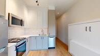 Located at 1339 NW 19th Ave in Portland's vibrant Northwest District, this efficiently designed studio maximizes every inch of its single-floor layout. Light hardwood flooring runs throughout, complementing a bright, white-and-neutral palette that lends the space an airy, contemporary feel.

The kitchen is well-appointed for its scale, featuring two-tone cabinetry with soft gray lower cabinets and white uppers, a classic subway tile backsplash, stainless steel appliances including a full-size refrigerator and dishwasher, and a stainless sink with modern fixtures. Track lighting and recessed ceiling lights ensure the kitchen is well illuminated. A built-in Murphy bed with a clean white cabinet finish is integrated seamlessly alongside the kitchen, offering a smart space-saving sleeping solution.

A large sliding glass door floods the living area with natural light and opens to a private balcony with open views of the surrounding Portland neighborhood. The bathroom is clean and functional, finished in white with matte black hardware accents, a vanity with storage, and a soaking tub. A dedicated nook houses a stacked washer and dryer, providing in-unit laundry convenience. A bold dark entry door with matte black hardware anchors the entryway with a modern, industrial touch.