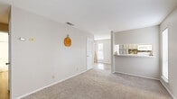 This single-floor, 2-bedroom, 1-bathroom residence offers a thoughtfully organized layout designed for comfortable everyday living. The open-concept living and dining area flows seamlessly into the kitchen, creating a connected and functional shared space. The living room features soft carpeted flooring, neutral warm-toned walls, and a window that allows natural light to fill the room. A hallway connects the main living areas to the private quarters of the home.

The kitchen is well-equipped with gray cabinetry, a white quartz-style countertop, a double-basin stainless steel sink with a modern pull-down faucet, a tile backsplash, and white appliances including a range, dishwasher, and refrigerator. Light wood-look flooring and multiple windows keep the kitchen bright and airy.

The primary bedroom offers a comfortable footprint with plush carpeting, two windows providing ample natural light, and generous closet space. The second bedroom is similarly carpeted and includes a built-in closet with bifold doors. The full bathroom features wood-look flooring, a vanity with a quartz-style countertop, and a tub-shower combination.

An outdoor deck with natural wood plank flooring, white vertical siding, painted brick walls, and a warm-toned horizontal railing extends the living space outdoors, offering a relaxing area to enjoy the fresh air.