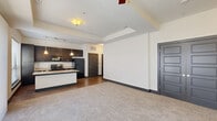 Located at 881 3rd Ave SW in Carmel, Indiana, this one-bedroom, one-bathroom residence offers a thoughtfully designed open-concept layout that seamlessly connects the living, dining, and kitchen areas. The kitchen is a standout feature, showcasing rich dark cabinetry that reaches toward the ceiling, a granite-topped island with a built-in wine rack and undermount sink, stainless appliances, a tile backsplash, and pendant lighting complemented by a track lighting system. Wood-look tile flooring runs throughout the kitchen and dining areas, while plush carpet adds warmth to the living room and bedroom. Large windows allow natural light to fill the main living space and bedroom, the latter of which also includes a ceiling fan. The bathroom is finished with tile flooring, a dual-sink dark vanity with framed mirrors, and a tiled soaking tub and shower combination. Three closets provide generous storage throughout the unit, including a spacious walk-in closet accessible from the bathroom. A dedicated laundry area houses a full-size front-loading washer and dryer. The consistent use of dark trim, paneled doors, and neutral tones throughout gives the space a cohesive, contemporary character.