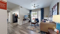 This single-floor residence offers a thoughtfully designed layout that balances comfort and functionality. The living area serves as the heart of the home, featuring wood-look flooring, a ceiling fan, and a large sliding glass door framed by bold navy patterned drapes that flood the space with natural light and provide direct access to a private outdoor patio. The open layout flows naturally between the living and dining areas, creating an inviting atmosphere accented by contemporary décor and vibrant artwork on the walls.

The galley-style kitchen is efficiently designed with white cabinetry, dark countertops, black appliances including a dishwasher and electric range, and a window that brings in additional natural light. The streamlined layout maximizes workspace and storage on both sides of the kitchen corridor.

The bedroom is a serene retreat, showcasing the same wood-look flooring, a ceiling fan, and large windows dressed with bright red curtains that add a striking pop of color. The room offers ample space for a full bedroom suite and is complemented by soft, neutral wall tones.

The full bathroom features white cabinetry with a dark countertop, a wide vanity mirror, and a shower-tub combination. Clean finishes and practical storage make this a well-organized and functional space. Throughout the residence, consistent flooring and a cohesive color palette create a harmonious and welcoming environment.