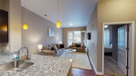Located at 4380 Eastgate Blvd in Cincinnati, Ohio, this single-floor residence offers a well-designed layout with a seamless flow between living, dining, and kitchen spaces. The open-concept living area features vaulted ceilings, warm hardwood-style flooring, and large sliding glass doors that lead to a private balcony, filling the space with natural light and outdoor views. A stylish pendant light and neutral wall tones contribute to the inviting ambiance.

The kitchen is outfitted with rich, dark cabinetry reaching the ceiling, stainless steel appliances including a refrigerator, range, and microwave, and granite countertops that extend to a breakfast bar with seating. The entryway features high ceilings, hardwood-style flooring, and built-in storage with white panel doors for added functionality.

The bedroom is a comfortable retreat with a ceiling fan, a large window framing natural views, and warm neutral tones throughout. The bathroom includes a granite-topped dark vanity with an oversized mirror, wood-look flooring, and a full tub-shower combination. Every room reflects a consistent, modern aesthetic with quality finishes, making this a polished and practical living space.