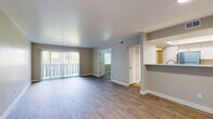 This single-floor residence offers a thoughtfully designed layout that balances open communal spaces with comfortable private areas. The main living area is expansive and bright, featuring warm wood-look flooring and large sliding glass doors fitted with vertical blinds that allow abundant natural light to filter in. A pass-through opening connects the living space to the kitchen, creating an open, airy feel ideal for everyday living and entertaining.

The kitchen is well-equipped, showcasing a two-tone cabinetry design with crisp white upper cabinets and slate-gray lower cabinets, complemented by light stone countertops. Stainless steel appliances, including a range with microwave hood and a full-size refrigerator, complete the functional cooking space. Wood-look flooring continues seamlessly throughout the kitchen.

The bedrooms are generously sized, each featuring plush wall-to-wall carpeting, neutral-toned walls, and windows with blinds that offer privacy while admitting natural light. Multiple closets provide ample storage throughout.

The bathrooms are finished to a high standard, featuring gray shaker-style vanity cabinets topped with light stone countertops. The primary bathroom boasts a double-sink vanity with a wide mirror and elegant sconce lighting, while the secondary bathroom includes a single vanity with in-unit laundry access. Clean white trim and neutral tones unify the overall aesthetic of the space.