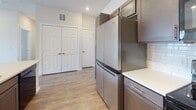 Located at 17744 Wayforest Dr in Houston, TX, this single-floor home offers a clean, modern design throughout. The open-concept layout connects the main living areas seamlessly, with warm wood-look laminate flooring extending through the living spaces and kitchen, creating a cohesive and inviting atmosphere. The living room is generously sized, featuring recessed lighting, a ceiling fan, and direct access to a private balcony through a glass door flanked by large windows that bring in abundant natural light and views of the surrounding neighborhood. The kitchen is well-appointed with dark, richly finished cabinetry, white countertops, a classic subway tile backsplash, and stainless steel appliances including a full-size refrigerator and microwave. Ample storage is provided by double closets nearby. The bedrooms are comfortably carpeted and include closets with sliding or paneled doors; one bedroom receives natural light through a window with a neighborhood view. The bathroom is finished with large-format light tile flooring, a dark-toned vanity with white countertop, a framed mirror, and a subway tile-surround tub and shower combination. Throughout the home, neutral tones and consistent finishes create a bright, move-in-ready environment.