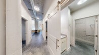 This thoughtfully designed 3-bedroom, 3-bathroom unit in Augusta, GA blends industrial character with modern finishes across a single floor. Polished concrete floors run throughout, complementing whitewashed exposed brick walls that appear in the kitchen, bedrooms, and hallways. Soaring ceilings with exposed ductwork add loft-style drama and a sense of openness well beyond the unit's footprint.

The kitchen is a standout, featuring sleek gray cabinetry, stainless steel appliances including a French door refrigerator, a white quartz waterfall island with seating, and subway tile backsplash. The open layout connects seamlessly to the living and dining areas, where arched windows invite natural light.

A wide hallway with a sliding barn door leads to the bathrooms, which feature white vanities with quartz countertops and shower-tub combinations. The primary bedroom is generously proportioned with dramatic ceiling height, a whitewashed brick accent wall, a walk-in closet, and a private en-suite bath. Additional bedrooms carry the same clean, bright aesthetic.

A dedicated laundry room houses a full-size washer and dryer with overhead shelving. The overall ambiance is bright, modern, and urban — a refined take on industrial living.