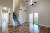 Located at 2285 Metropolitan Pkwy SW in Atlanta, GA, this two-story, 3-bedroom, 3-bathroom home offers a well-designed layout spread across two floors. The main level commands attention with dramatic vaulted ceilings that rise through the open living room, filling the space with an airy, expansive feel. Rich hardwood-style flooring runs throughout the main living areas, complemented by neutral warm-toned walls and ceiling fans. A sliding glass door in the living room allows natural light to pour in while providing outdoor access. The kitchen features warm wood cabinetry, granite countertops, a tile backsplash, stainless steel appliances, and a breakfast bar peninsula that connects seamlessly to the living area. A carpeted staircase leads to the upper level, where additional living space awaits. The generously sized primary bedroom includes vaulted ceilings, a sliding glass door, and a walk-in closet with built-in shelving. The primary bathroom is appointed with tile flooring, a soaking tub with tile surround, a large vanity mirror, and granite countertops. Additional bedrooms are bright and well-proportioned, with large windows offering natural views. Four closets throughout the home ensure ample storage. The overall ambiance is clean, open, and move-in ready.