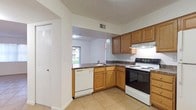 This single-story residence offers a practical and well-organized layout highlighted by consistent design choices throughout. The open living and dining area is finished with large-format light ceramic tile flooring, creating a bright and cohesive space. A textured ceiling runs throughout the common areas, adding subtle visual depth. The kitchen is positioned adjacent to the main living space and features an L-shaped layout with warm honey-toned wood cabinetry, dark laminate countertops, a built-in dishwasher, electric range, and a pass-through window that maintains a visual connection to the living area. A window in the kitchen allows natural light to enter the space. A dedicated laundry closet within the unit houses a stacked washer and dryer, adding everyday convenience. The bedrooms are carpeted and each equipped with ceiling fans fitted with integrated lighting. Several bedrooms feature sliding glass doors or windows with vertical blinds, allowing natural light and outdoor views. One bedroom includes a spacious walk-in closet with wire shelving for organized storage. The bathroom is fitted with a full tub-shower combination surrounded by clean white square tile. Overall, the residence presents a functional and neatly maintained living environment.