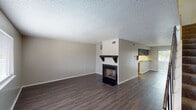 This two-story townhome in Port Arthur, Texas offers a well-organized layout across two levels, finished with dark hardwood-style flooring that flows consistently throughout the main living areas. The ground floor opens to a spacious living room anchored by a striking wood-burning fireplace with a dark mantel and glass-front surround, creating a natural focal point in the room. A staircase with a metal railing leads to the upper level, and large windows allow natural light to brighten the entry area. The kitchen features bold navy upper cabinetry, granite-style countertops, a peninsula breakfast bar, and white appliances including a range and refrigerator. A half bath is conveniently located on the main floor, fitted with dark cabinetry and a granite-style vanity top. Upstairs, two generously sized bedrooms each feature ceiling fans, textured ceilings, and hardwood-style flooring. The primary bedroom includes dual closets and access to a private balcony, while the secondary bedroom offers its own closet and a sliding glass door with natural light. The full bathroom upstairs is equipped with a wide vanity, dark cabinetry, and ample counter space. This townhome combines practical storage, comfortable living areas, and distinct design details throughout.