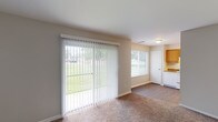Located at 7901 Madison Ave in Indianapolis, Indiana, this single-floor unit offers a practical and comfortable layout with well-defined living spaces throughout. The living area is a highlight of the home, featuring warm neutral-toned walls, plush carpeting, and a full-length sliding glass door dressed with vertical blinds that opens to an outdoor view of lush green grounds, allowing abundant natural light to fill the room. An additional window further brightens the space, creating an open and airy atmosphere. The kitchen is efficiently designed with warm honey-toned wood cabinetry, dark laminate countertops, wood-style flooring, and white appliances including a range and refrigerator, offering ample storage and workspace. The bedrooms are generously proportioned, each finished with soft carpeting and windows fitted with blinds for privacy and light control. One bedroom includes a built-in closet with shelving, providing organized storage. The bathroom features a clean, all-white design with a shower-tub combination, a vanity with under-sink storage, wood-style flooring, and a bright, functional layout. Throughout the unit, neutral color palettes and consistent finishes create a cohesive and move-in-ready environment.