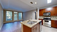 Located in the Northlake Heights community of Atlanta, GA, this well-appointed 2-bedroom, 3-bathroom residence offers a thoughtfully designed single-floor layout. The open-concept kitchen and living area serves as the heart of the home, featuring a central island with a double stainless steel sink and granite countertops, rich cherry wood cabinetry, and a full suite of stainless steel appliances including a range, microwave, and dishwasher. The living room is bathed in natural light through large windows and a glass door that opens to a private balcony with tree-lined views, all accented by hardwood-style flooring and elegant crown molding throughout. The two bedrooms are carpeted and generously sized, with the primary bedroom offering access to a dedicated closet and en-suite bathroom. The bathrooms are finished with tiled tub-shower combinations featuring decorative mosaic accent bands, warm wood vanities, and framed mirrors. A dedicated in-unit laundry room houses a full-size washer and dryer. Two closets provide ample storage, and a hallway connects the private sleeping quarters to the main living spaces, creating a functional and comfortable flow throughout the home.