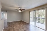 Located at 101 Porpoise Bay Road in Daytona Beach, Florida, this two-bedroom, one-bathroom residence offers a well-organized single-floor layout designed for comfortable everyday living. The combined living and dining area serves as the heart of the home, featuring wood-style plank flooring, a ceiling fan with light fixture, and a textured ceiling. A sliding glass door opens directly onto a private balcony, where lush palm tree views provide a distinctly Florida ambiance. The kitchen is equipped with white cabinetry, a black refrigerator and electric range, and a pass-through counter that connects seamlessly to the living and dining space. Both bedrooms feature ceiling fans and soft carpeting. The primary bedroom is generously sized and includes dual closets with louvered bifold doors, providing ample storage. The second bedroom offers its own closet and convenient access to the shared full bathroom, which includes a tiled shower/tub combo and a white vanity. A dedicated in-unit laundry area accommodates a full-size washer and dryer side by side, with overhead wire shelving for added storage. A hallway connects all areas of the home, with additional closets enhancing overall storage capacity throughout this practical and comfortable Daytona Beach residence.