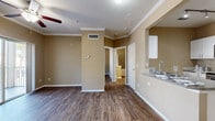 Located at 8580 29th Way N in Pinellas Park, Florida, this two-story residence offers a well-organized layout spread across two levels. The ground floor houses a private, enclosed garage with an automatic door and a clean epoxy-coated concrete floor, providing secure parking and additional storage space.

The upper level serves as the main living area, featuring warm, wood-look plank flooring throughout and neutral tan walls accented by crisp white crown molding and baseboards. The open living room is finished with a ceiling fan and sliding glass doors that lead to a private balcony with outdoor views. The galley-style kitchen is well-appointed with white cabinetry, granite-look countertops, stainless steel appliances including a refrigerator, electric range, microwave, and dishwasher, and light tile flooring. A dedicated laundry area is conveniently accessible from the kitchen.

The spacious bedroom features wood-look flooring, a ceiling fan, a large window that brings in natural light, and access to multiple closets, including a generously sized walk-in closet outfitted with wire shelving. The full bathroom offers a combined tub and shower with tile surround, a vanity with storage, and hardwood-style flooring. Two staircases connect the floors, contributing to the home's functional flow.