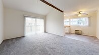 Located at 10542 Westminster Ave in Garden Grove, California, this single-floor, 2-bedroom, 2-bathroom residence offers a thoughtfully designed layout with a warm, neutral aesthetic throughout. The living area immediately impresses with its vaulted ceiling accented by a distinctive exposed wood beam, creating a sense of openness and architectural character. Large vertical-blind sliding doors flood the space with natural light and provide direct access to a private balcony. Soft carpeting runs throughout the main living areas and bedrooms, contributing to a comfortable, cohesive feel. The adjoining dining room and kitchen area benefit from additional natural light through generous windows. The spacious primary bedroom features crown molding, a sliding-door closet, and its own window with vertical blinds, while the second bedroom mirrors a similarly bright and tidy design. Three closets in total provide ample storage throughout the home. Both bathrooms are finished with light wood-look flooring, stone-topped vanities, and clean white fixtures — one featuring a tub-shower combo and the other a tile-surround walk-in shower with sliding glass doors. A hallway connects the rooms efficiently, completing this well-appointed and functional single-level home.