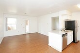 This single-floor residence offers a thoughtfully designed layout that balances open communal spaces with comfortable private areas. The living area is expansive and filled with natural light streaming through multiple windows, featuring warm hardwood-style flooring that extends throughout the main living spaces. A set of glass-paneled doors provides outdoor access, enhancing the bright and airy atmosphere.

The kitchen is efficiently designed with white shaker-style cabinetry, granite-look countertops, and stainless steel appliances including a refrigerator, electric range with overhead ventilation, and a dishwasher. A peninsula counter separates the kitchen from the living area, creating a natural flow between the two spaces.

The bedrooms are carpeted for comfort and bathed in natural light from large multi-pane windows that offer pleasant outdoor views. Each bedroom includes closet space with built-in racking, providing practical storage solutions.

The bathroom is clean and functional, featuring a full tub-shower combination with a curtain rod, a white vanity with granite-style countertops, and hardwood-style flooring. The space is finished with neutral tones throughout, lending a cohesive and inviting feel to the entire residence.