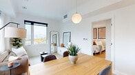 Located steps from Montréal's iconic Old Port, this 2-bedroom, 2-bathroom unit offers a thoughtfully designed layout with a clean, modern aesthetic throughout. Light oak hardwood flooring runs continuously across the space, complementing the bright white walls and recessed lighting that create a fresh, airy atmosphere.

The open living and dining area is anchored by large windows that frame sweeping city views, flooding the space with natural light. The galley-style kitchen features flat-front cabinetry in warm wood and white tones, a sleek black induction cooktop, integrated appliances, and generous countertop space — a functional yet stylish setup.

The primary bedroom is a serene retreat, finished with light wood floors, a built-in sliding-door closet, and soft wall sconces. The second bedroom is equally well-appointed. Both bathrooms are finished with large-format tiles and modern chrome fixtures, including a walk-in glass shower in one.

A well-proportioned hallway connects the rooms efficiently, accented by black steel open shelving and curated wall art. The overall design language is minimalist and cohesive, with a neutral palette and contemporary detailing that give the space a refined, livable character well-suited to urban life in Montréal.
